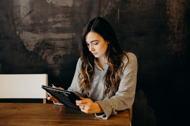 Mujer sentada en un escritorio observando su tablet